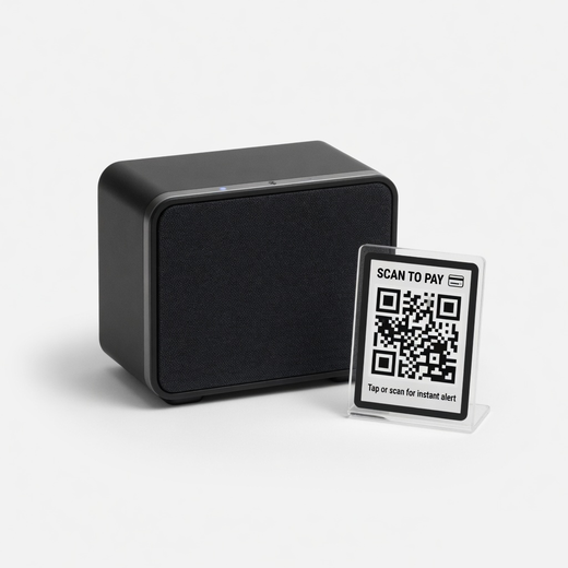 Compact black Bluetooth speaker beside a small acrylic Scan to Pay QR stand
